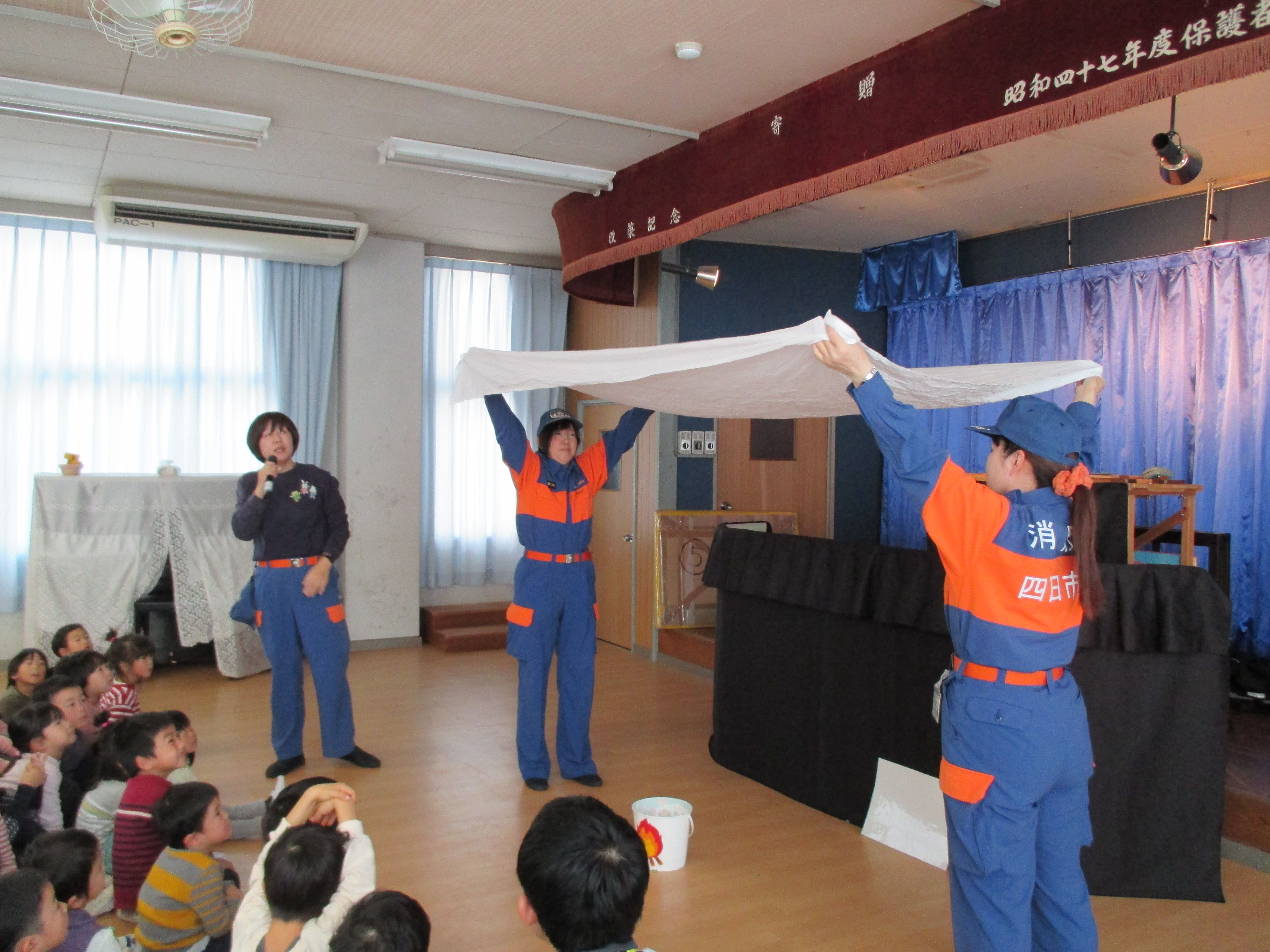 住宅用火災警報器やシーツを使って火災の煙について説明する様子