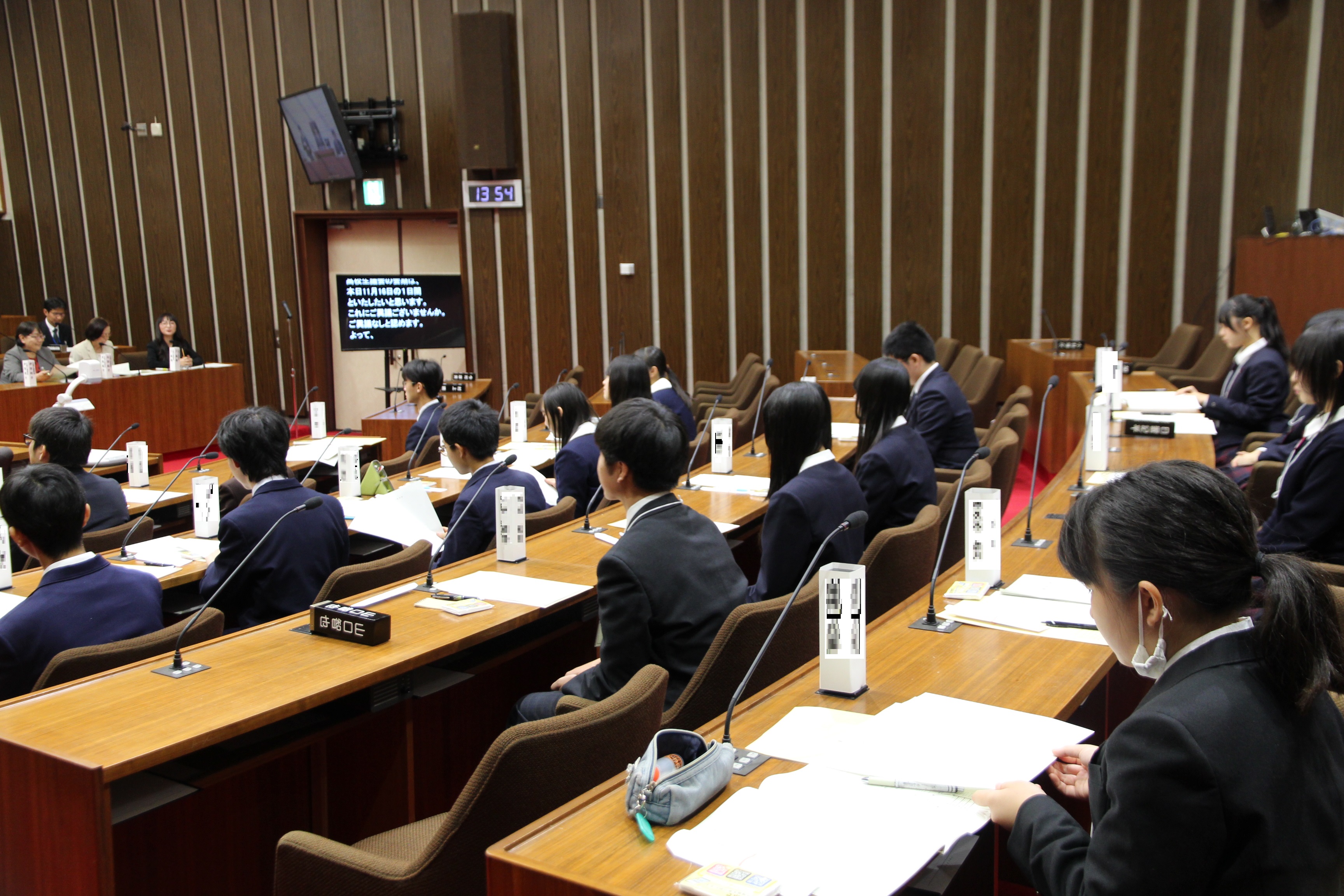議席で委員会付託の説明をきく高校生議員