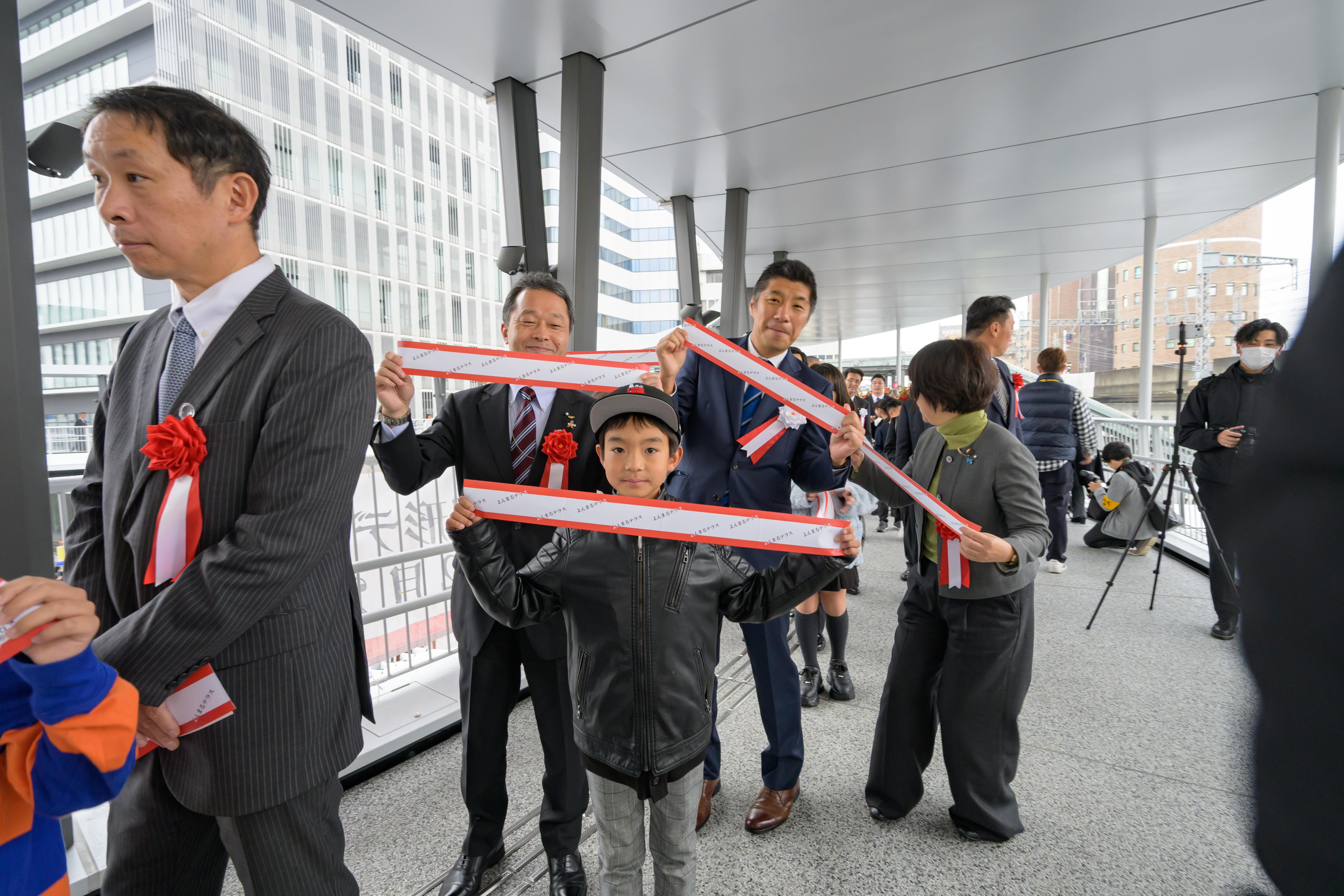 テープカットをしたテープを手にポーズを決める参加者と市長、知事